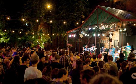 People at a small outside concert, behind a bar